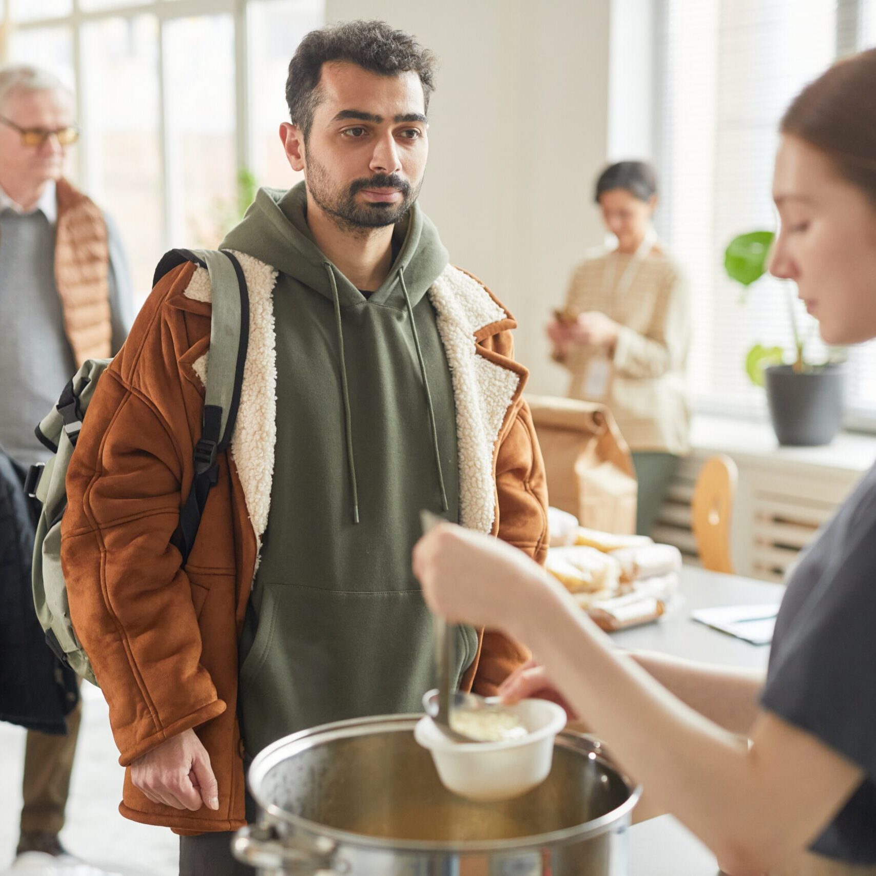 Portrait,Of,Young,Man,Standing,In,Line,At,Soup,Kitchen